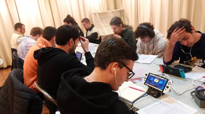 Personas concentradas jugando con consolas Nintendo Switch en una mesa larga durante el Midseason Showdown de Herrera de Pisuerga