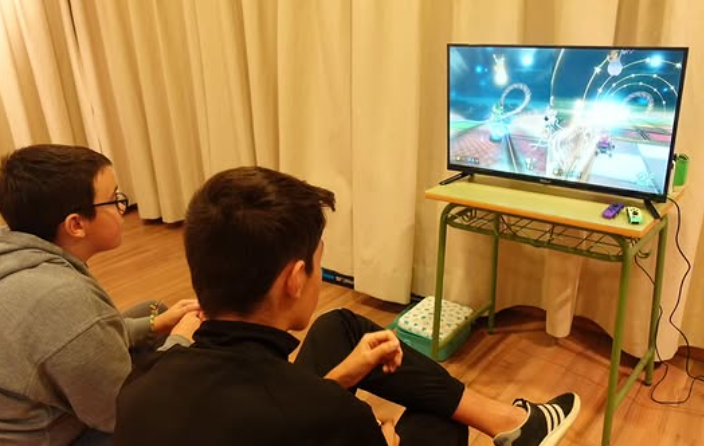 Dos chicos sentados en el suelo jugando a Mario Kart frente a una televisión durante la sesión de Free Play en Herrera de Pisuerga