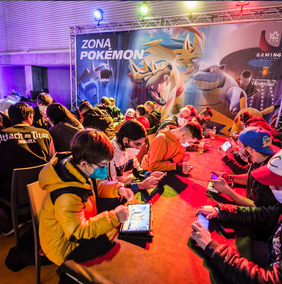 Participantes jugando con dispositivos en las mesas de la Zona Pokémon de UltraLan Valladolid